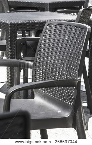 Empty black plastic tables and chairs on a terrace