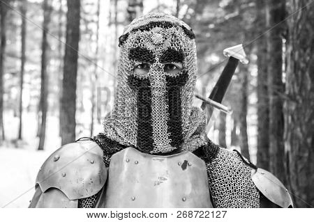 Knight In Armor And With A Sword In The Middle Of A Winter Forest. Vintage Military Uniform.