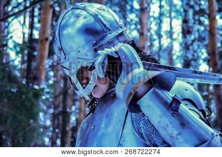 Knight In Armor And With A Sword In The Middle Of A Winter Forest. Vintage Military Uniform.