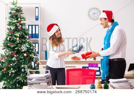 Colleagues exchaing christmas presents in office
