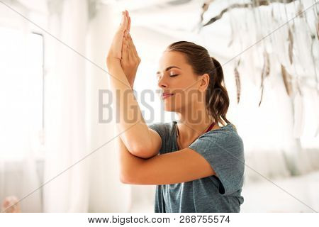 mindfulness, spirituality and healthy lifestyle concept - woman meditating at yoga studio