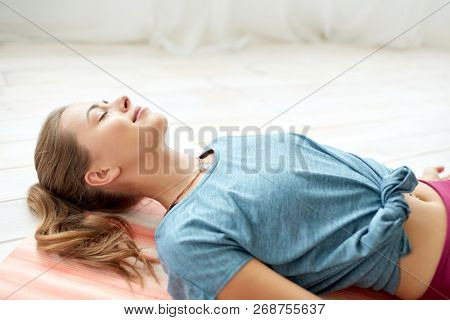 fitness, sport and healthy lifestyle concept - woman doing yoga corpse pose at studio