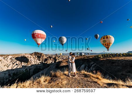 Couple in love among balloons. A guy proposes to a girl. Couple in love in Cappadocia. Couple in Turkey. Honeymoon in the mountains. Man and woman traveling. Flying on balloons. Wedding. Journey. Love