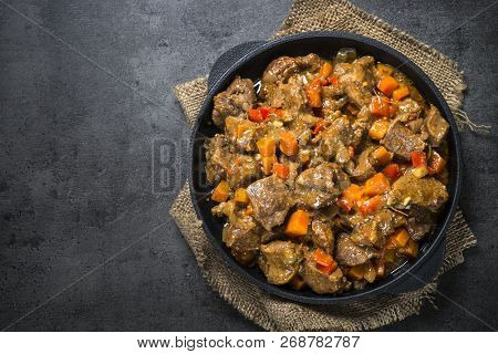 Beef Stew With Vegetables In Iron Pan On Black Background. European Cuisine. Top View.