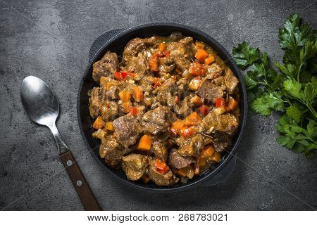 Beef Stew With Vegetables In Iron Pan On Black Background. European Cuisine. Top View.