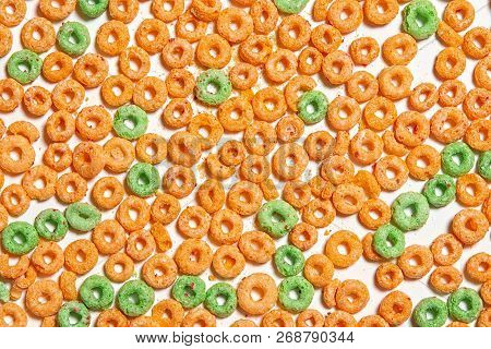 Background Of Colorful Cereal Rings. Green And Orange Cereal Rings On White Background. Flat Lay, To