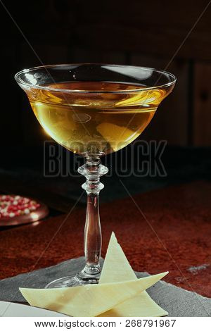 Yellow cocktail based on white wine in a beautiful goblet glass served  with parmesan cheese  on a  copper background. close-up. Series of photo.