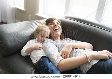 Happy Mother With Her Daughter On The Sofa In The Living Room At Home