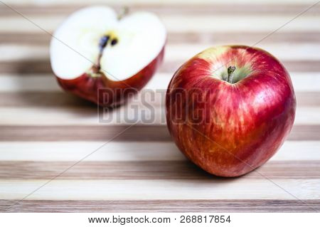 Red Apple Next To Slices Of Another Apple.