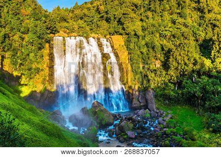The unusually wide Marokopa falls at sunset. Exotic journey to the North Island, New Zealand. Concept of active and ecological tourism