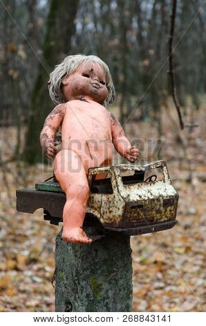 Children's Doll And Rusty Car Near Abandoned Kindergarten In Destroyed Village Of Kopachi (chernobyl