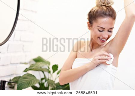 Young woman using deodorant in bathroom