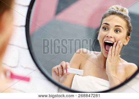 Young woman with pregnancy test in bathroom