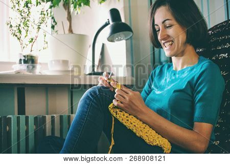 Woman Knits Crochet. The Girl Sits On The Couch And Knits From Knitting Yarn. Crochet Thick Threads.