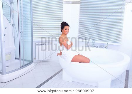 Joven hermosa mujer asiática sentada en el cuarto de baño moderno con jakuzzi