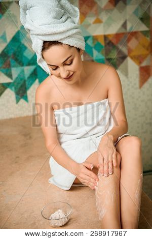 Smiling Girl Applying Scrub While Sitting On Hammam Table In Turkish Bath