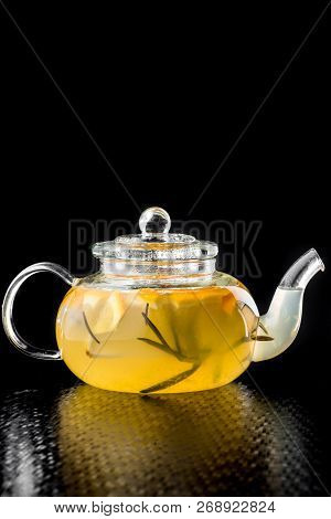 Citrus tea with lemon, iber and lemon in a transparent beautiful teapot isolated on a black background. close-up. space. isolated