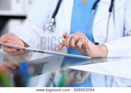 Woman Doctor Using Tablet Computer While Sitting At The Desk  In Hospital Office, Closeup. Healthcar