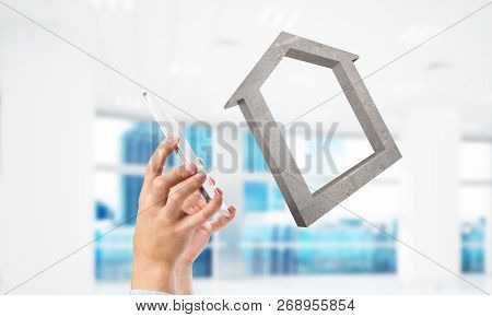 Cropped Image Of Businessman In Suit And Stone House Symbol In Hands. Mixed Media