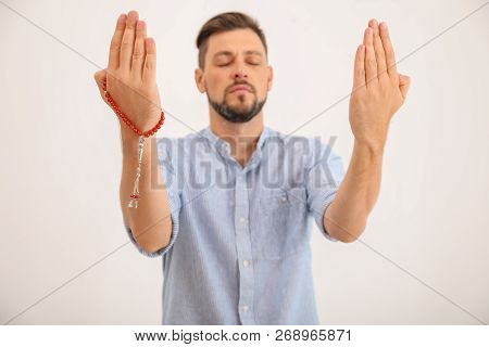 Muslim Man With Misbaha Praying On Light Background