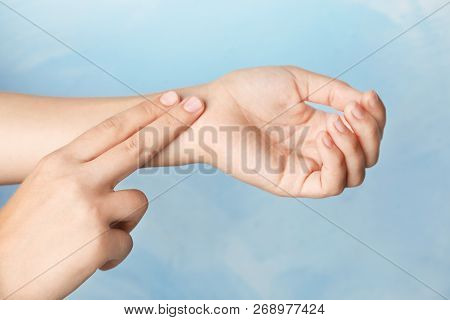 Woman Checking Pulse On Wrist Against Color Background, Closeup