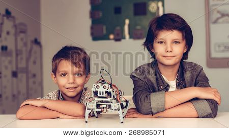 Two Boys Sitting At Table And Constructing Robot. Young Boy In Shirt. Indoor Joy. Modern Hobby Conce