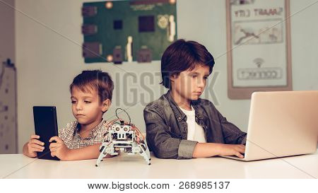 Two Boys Sitting At Table And Programming Robot. Young Boy In Shirt. Indoor Joy. Modern Hobby Concep