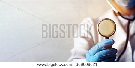 Doctors Hand In Blue Surgical Gloves, With A Stethoscope In His Hands.