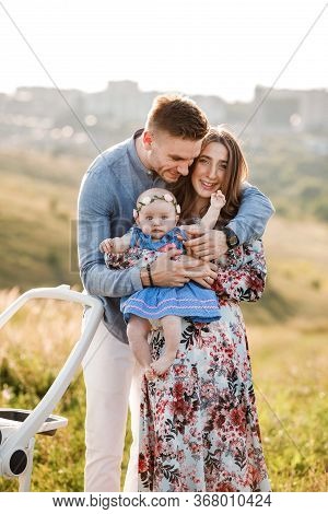 Mom, Dad And Little Girl Having Fun Outdoors In The Grass On Summer Day. Mothers, Fathers And Babys 