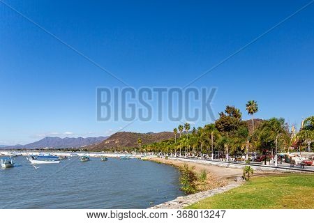 Boardwalk Along The Bay Of Lake Chapala With Motorboats On The Calm Waters, The Pier And Mountains I