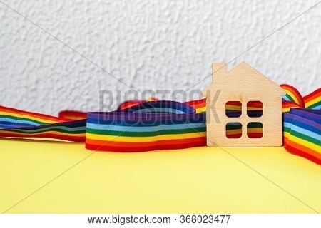 Mini Toy Wooden House And Lgbt Rainbow Ribbbon On Yellow Background, Copy Space