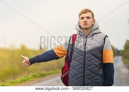 Tired Young Man Traveler Trying To Stop, Catch Taxi Car, Cab. Handsome Guy Stands Near The Road And 