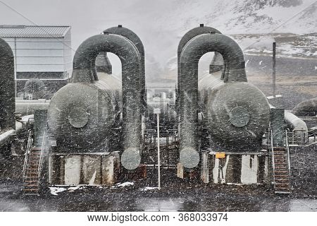 Geothermal power plant in Iceland, pipe stuctures and pressure tanks in heavy snow fall blizzard