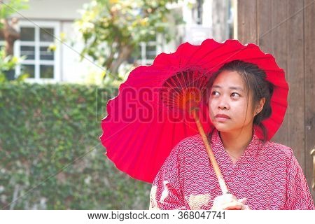 Soft Focus On Traditional Japanese Yukata Young Girl With Red Umbrella In Garden, Asian Girl In Yuka