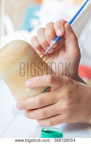 A Child Paints A Wooden Blank Of A Nesting Doll. Children's Crafts