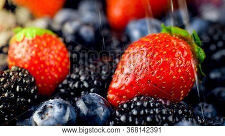Macro Image Of Water Dropelts Falling On Fresh Strawberries, Blueberries And Blackberries. Rain Over