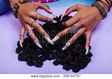 Woman Hands With Long Nails Manicure Holding Dry Fruits In Shape Of Heart On Purple Background