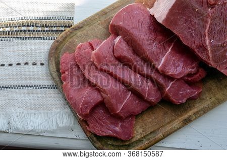 Portioned Slices Of Raw Meat On A Cutting Board. Fresh Pieces Of Chopped Beef Tenderloin Close-up. F