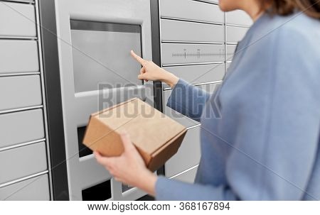 mail delivery and post service concept - close up of happy smiling woman with box at outdoor automated parcel machine choosing operation on touch screen