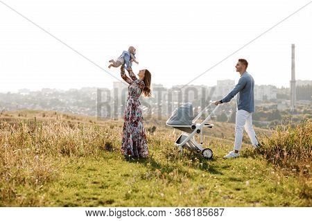 Mom, Dad And Little Girl Having Fun Outdoors In The Grass On Summer Day. Mothers, Fathers And Babys 