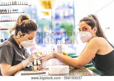 Latin Girl With Face Mask Painting Colored Nails To The Caucasian Brunette Client. Reopening After T