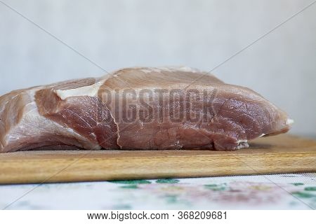 A Piece Of Pork Lies On A Wooden Plank On The Table  On A Sunny Day. Healthy Eating And Cooking At H