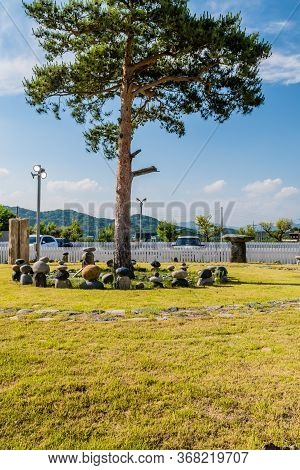 Gimcheon, South Korea; May 24, 2020: Tree In Middle Of Stone Stacks With Picket Fence And Blue Sky I
