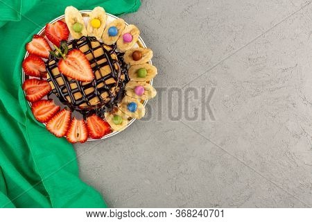 A Top View Pancakes Along With Poured Chocolate Sliced Strawberries And Bananas On The Light Backgro