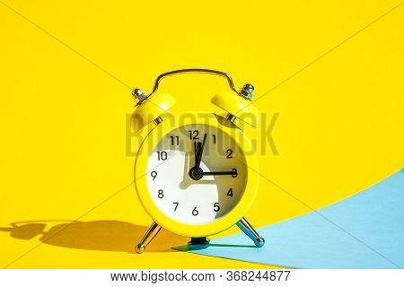 Yellow Vintage Alarm Clock On A Blue And Yellow Background With Selective Focus, Copy Space For Text