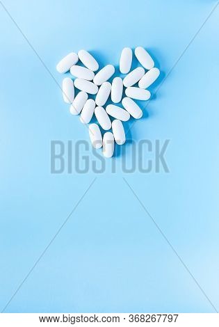 Pills Of Vitamin In The Shape Of Heart On Soft Blue Background