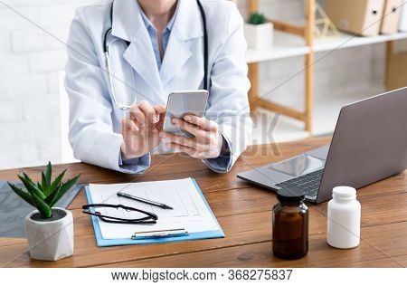 Remote Online Patient Consultation. Female Doctor Typing On Phone, On Table With Pills, Tablets And 