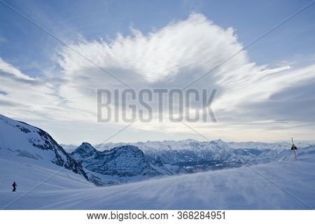 A Heart Shaped Cloud Floats Over A Ski Run As Part Of An Expansive Mountain Vista In The Italian Alp