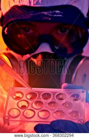COVID-19 or 2019-nCoV. Close-up portrait of a scientist microbiologist in a protective PPE suit making a research on blood samples of infected people.