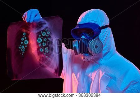 COVID-19 or 2019-nCoV. Portrait of a doctor in a protective PPE suit showing an x-ray picture of the lungs of a patient with coronavirus pneumonia. 